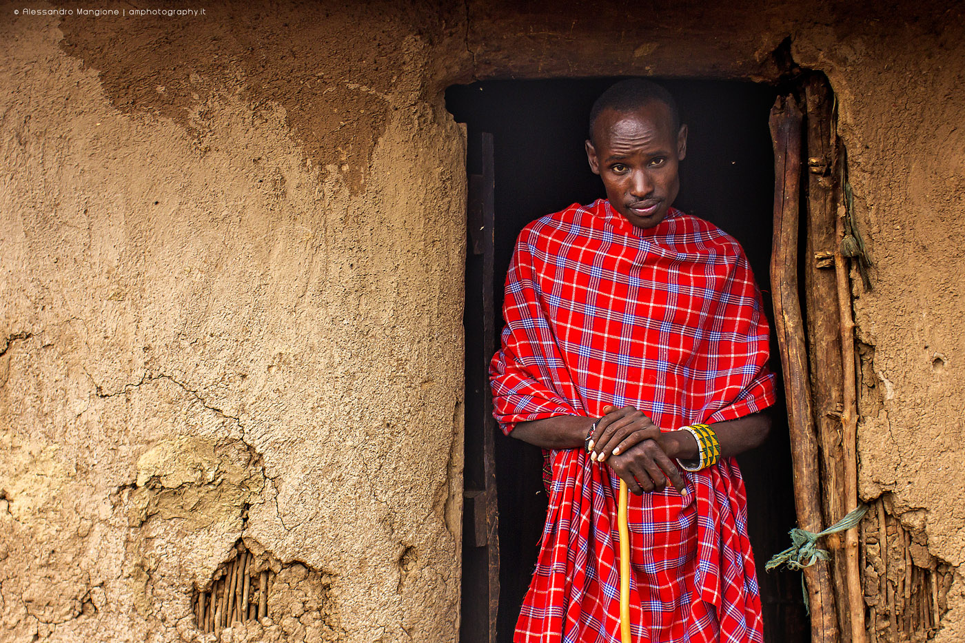 Maasai man in front of a traditional house